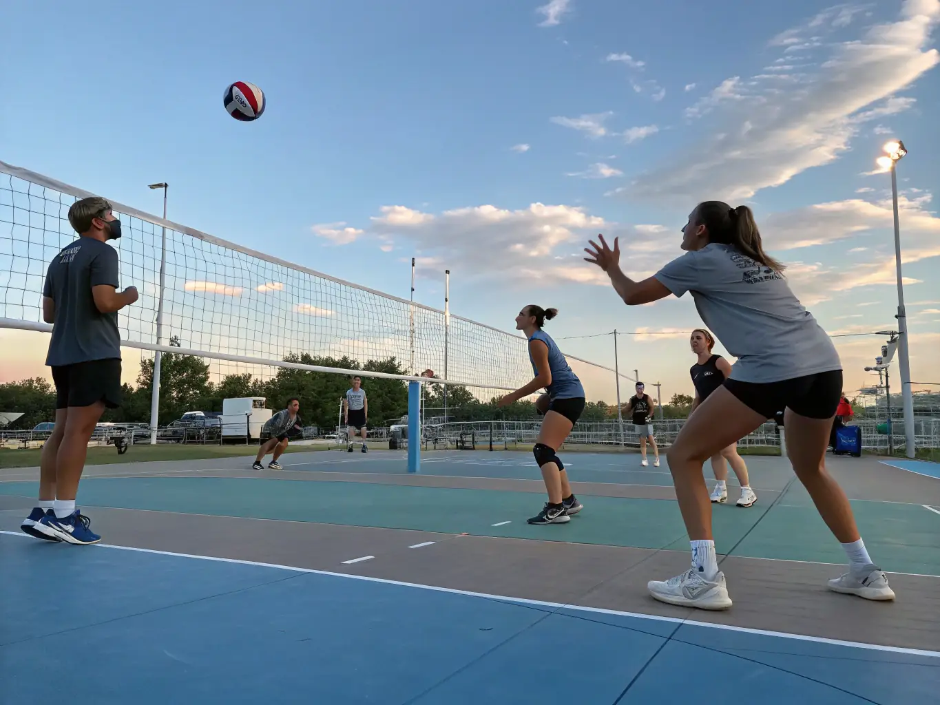 An image of a diverse group of players participating in a community volleyball training session on an outdoor court, with a coach providing guidance and instruction.